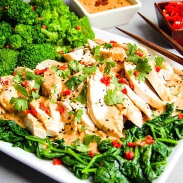 Chicken and spinach on a serving platter with peanut sauce.