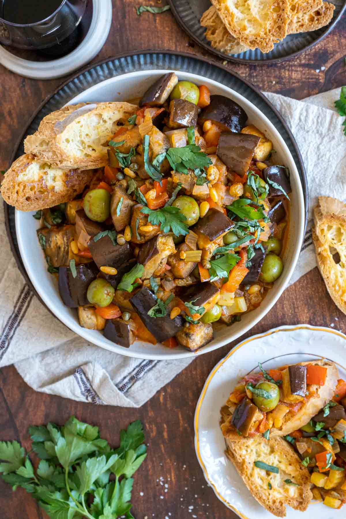 Caponata in a bowl with toasted bread and a plate of bruschetta.
