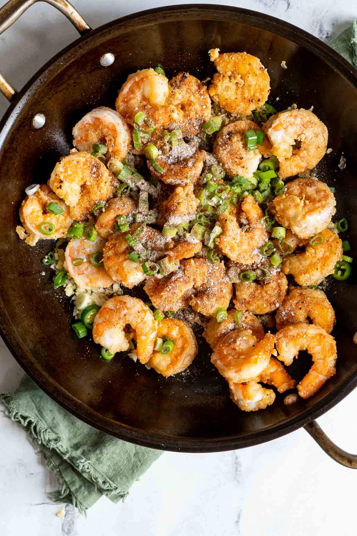 Adding the salt and pepper spice mixture to the fried shrimp in a pan.