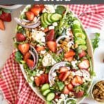 Spinach and arugula salad with strawberries on a platter.