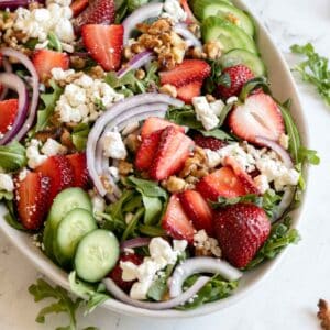 Goat cheese and strawberries on a salad with walnuts.