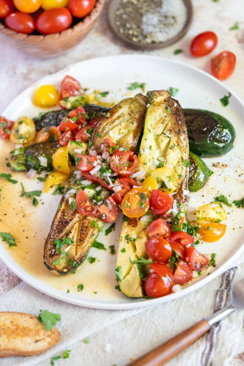 Roasted zucchini on a plate with tomatoes.