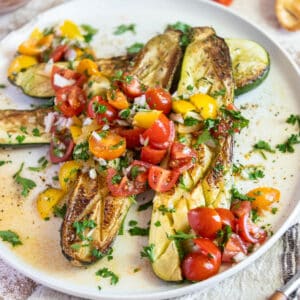 Roasted zucchini on a plate with tomatoes.