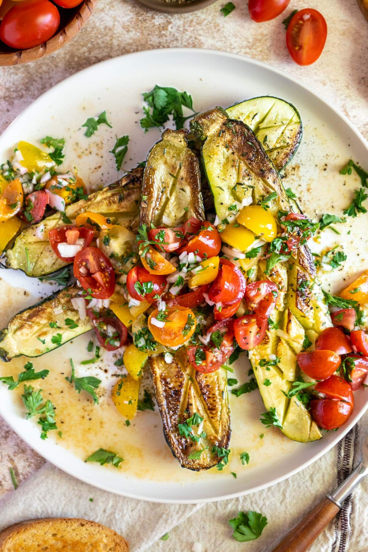 Roasted zucchini on a plate with tomatoes.