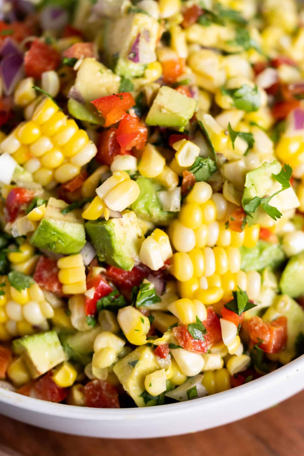 Avocado corn salad with red peppers in a bowl.