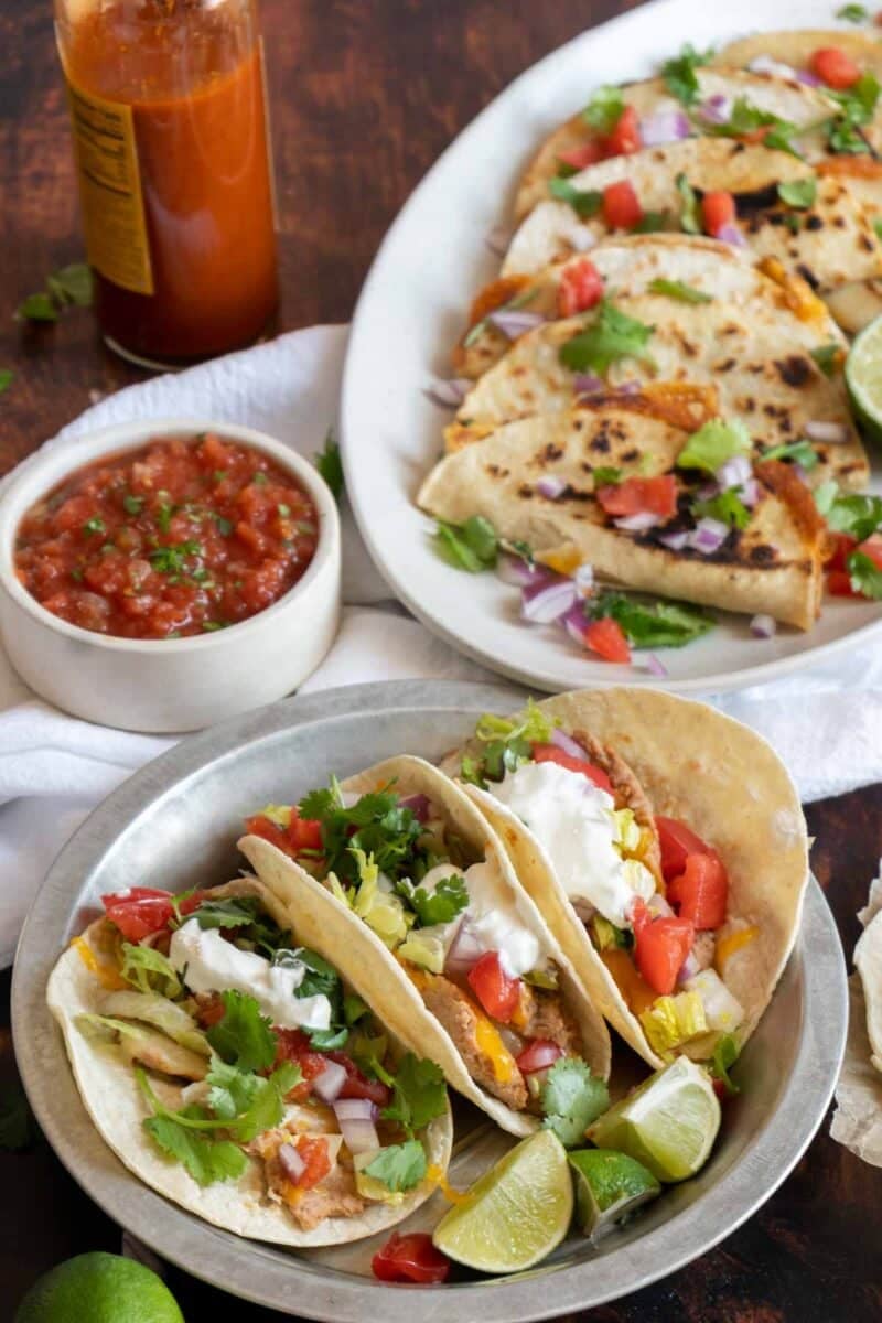 Bean and cheese tacos on platters. Some soft and some crispy.