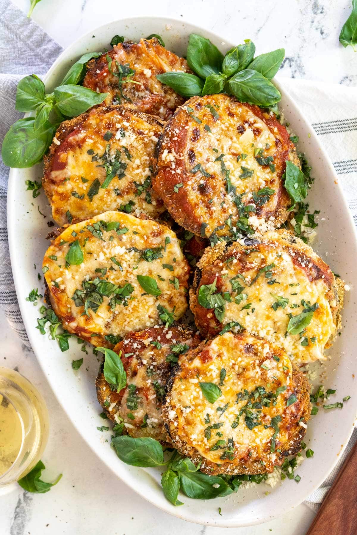 Eggplant parmesan on a serving plate with basil.