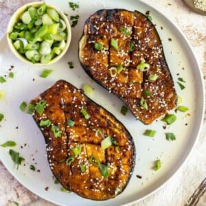 Miso eggplant with scallions and sesame on a plate.