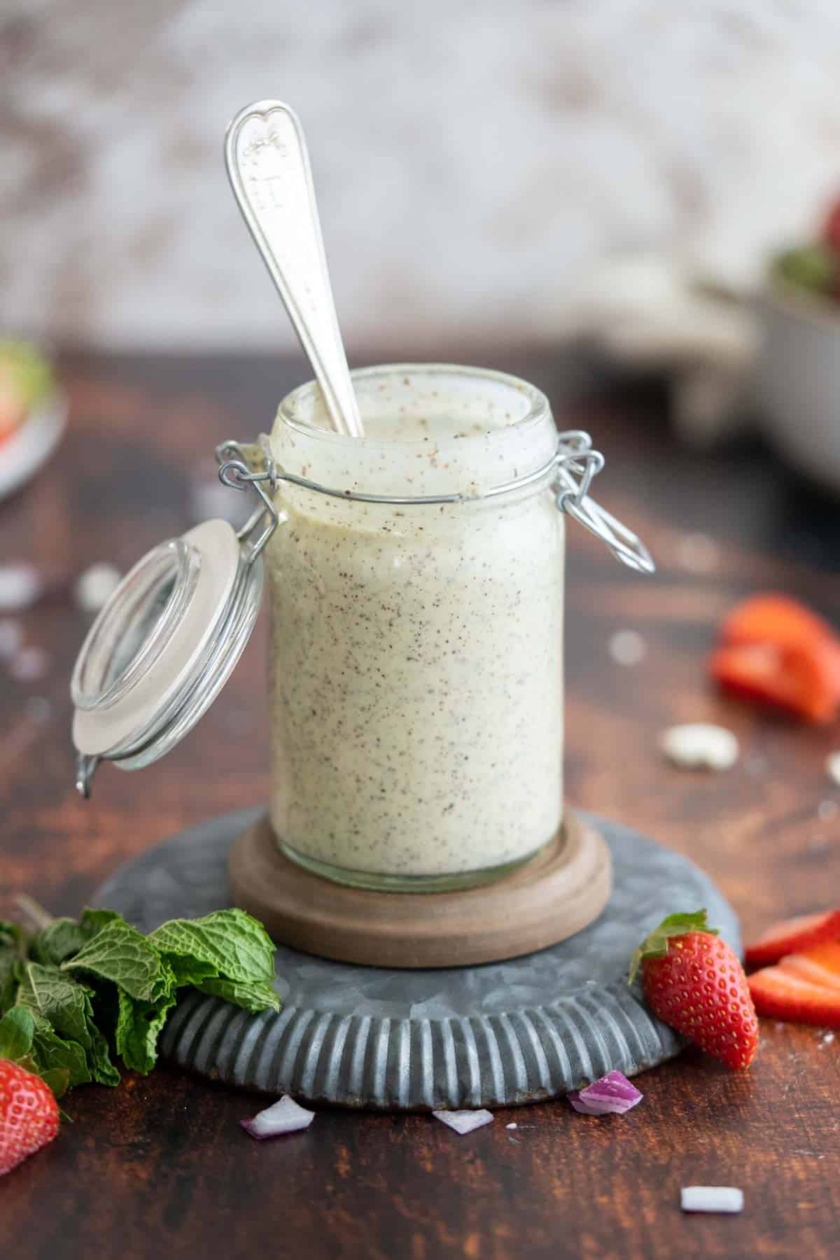 Creamy poppy seed dressing in a bottle with strawberries.