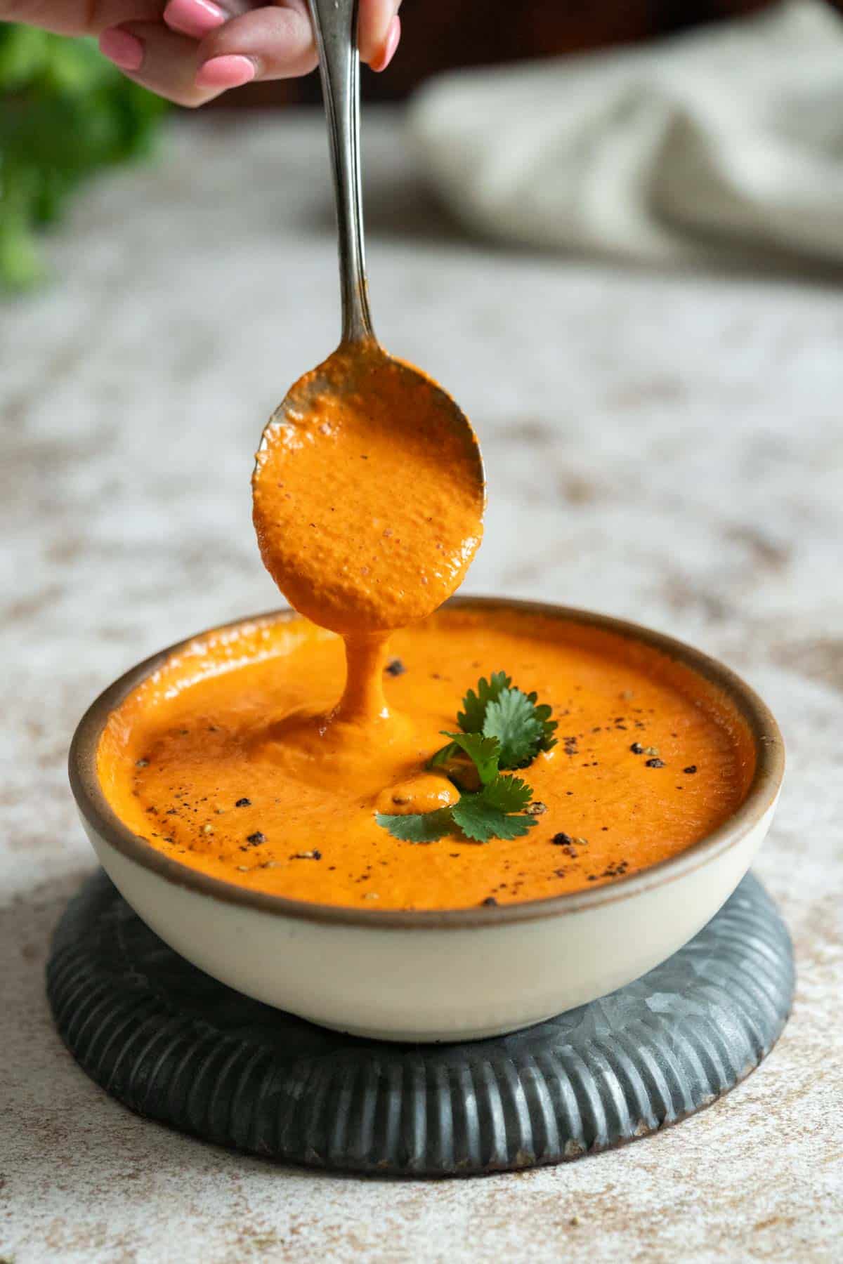 Spooning red pepper crema into a bowl.