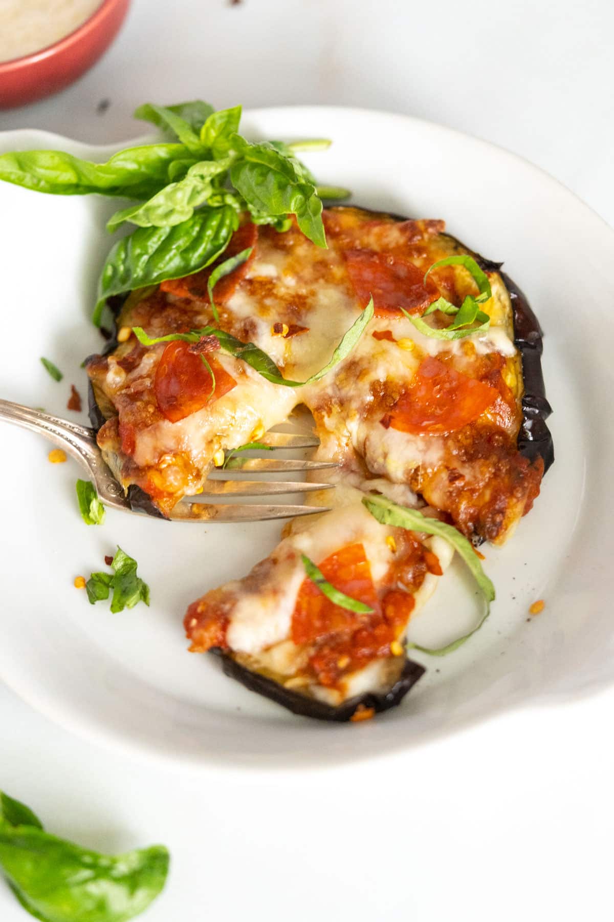 An eggplant pizza on a plate with a bite out of it.