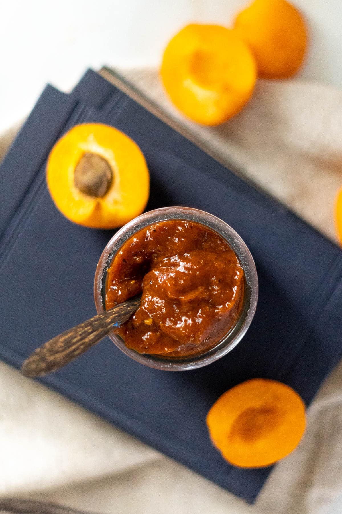 BBQ sauce in a jar with wooden spoon and sliced apricots.