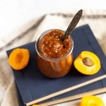 BBQ sauce in a jar with wooden spoon and sliced apricots.