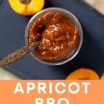 BBQ sauce in a jar with wooden spoon and sliced apricots.