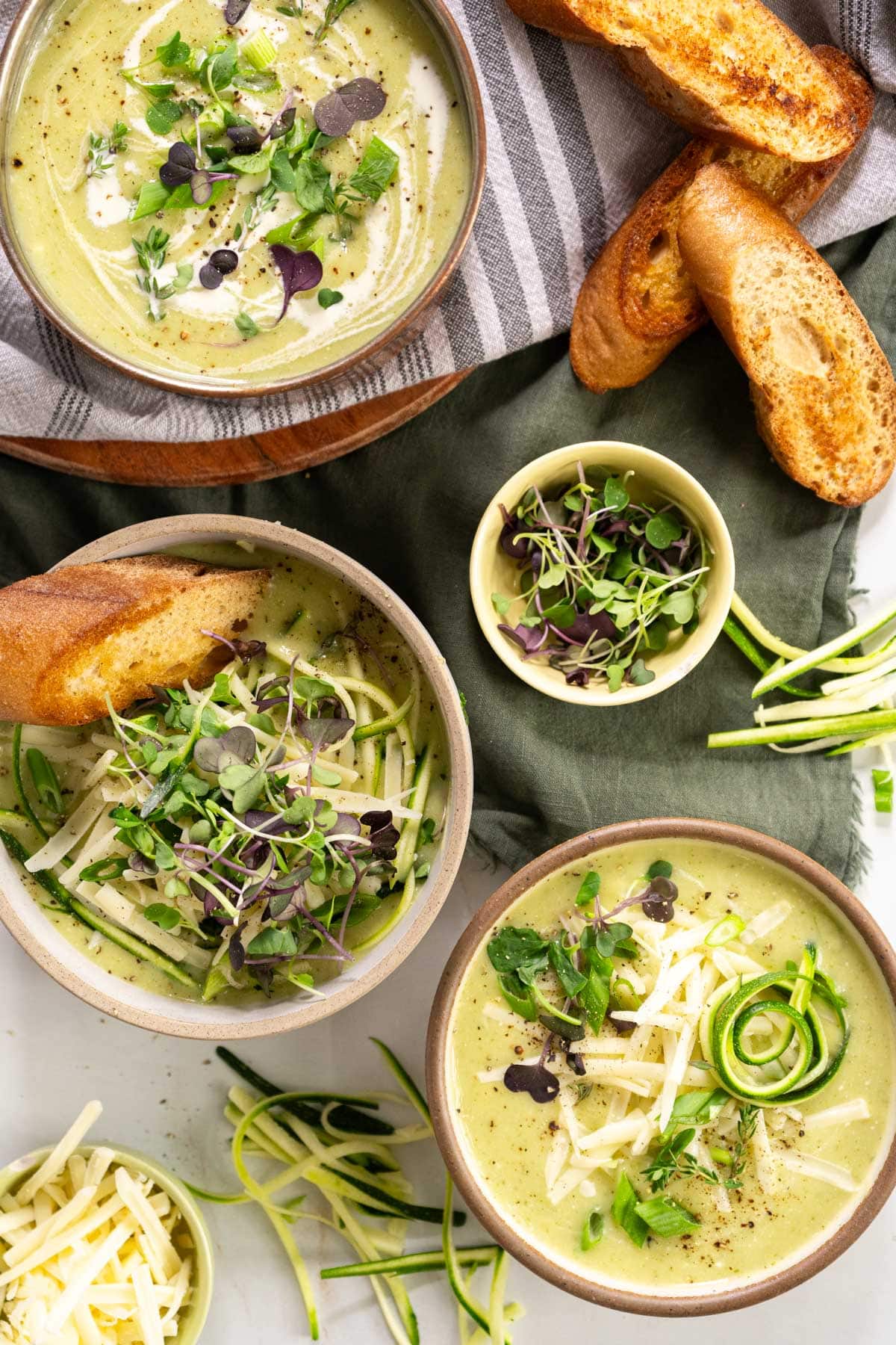 Three bowls of soup with slices of toasted bread.