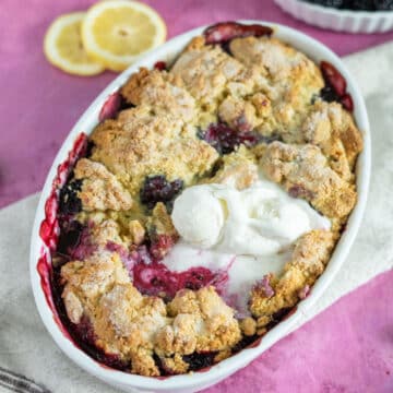 Gluten free blackberry cobbler in a baking dish with ice cream on top.
