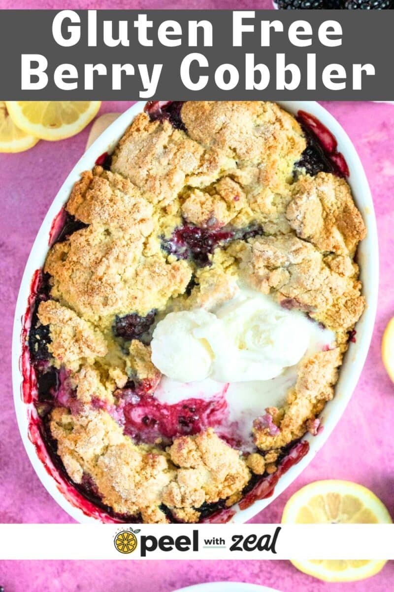Blackberry cobbler in a baking dish with ice cream and lemon slices.