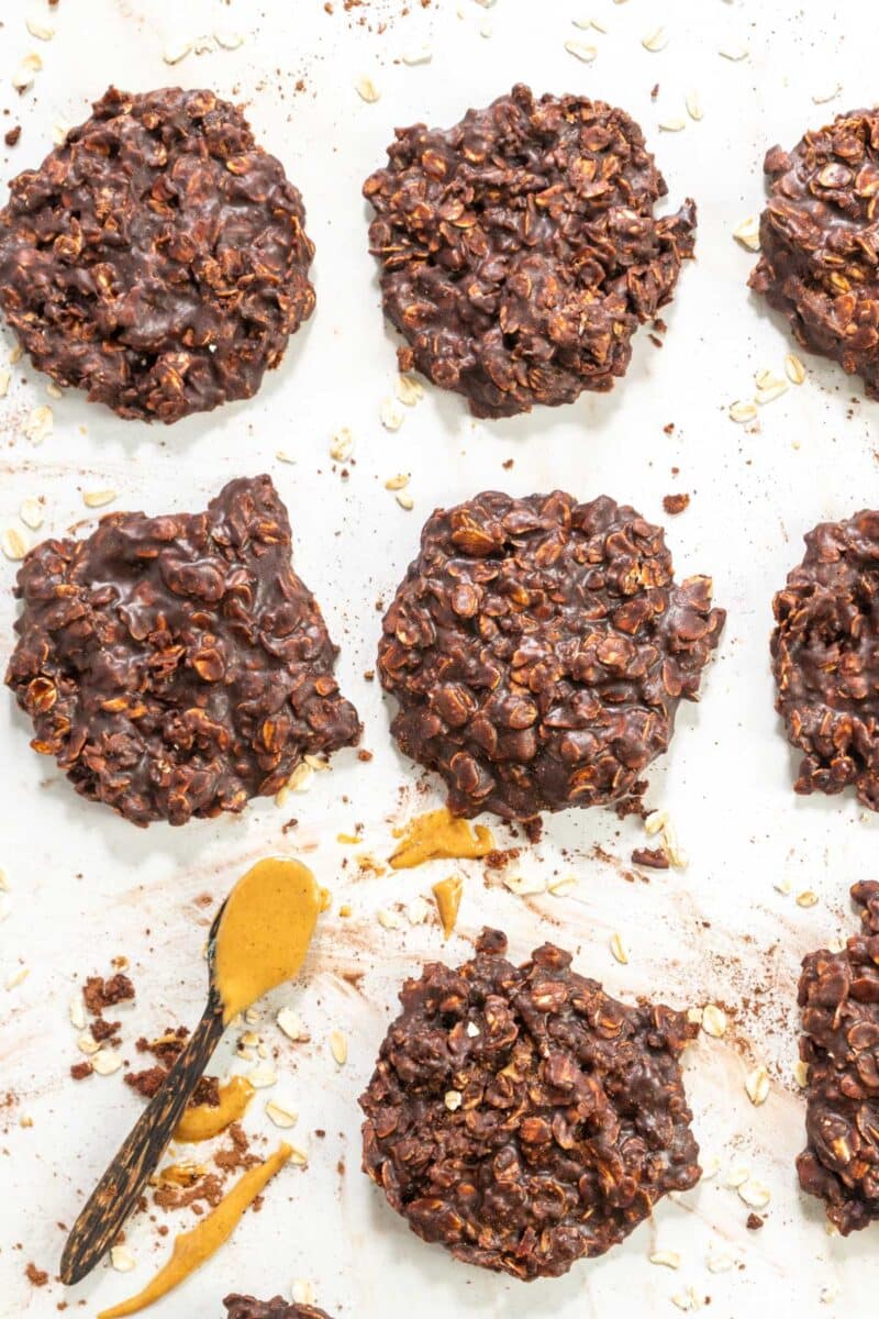 Gluten free no bake cookies on wax paper with a spoon of peanut butter.