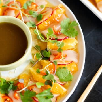 Hamachi crudo with orange slices, soy dipping sauce, and cilantro.