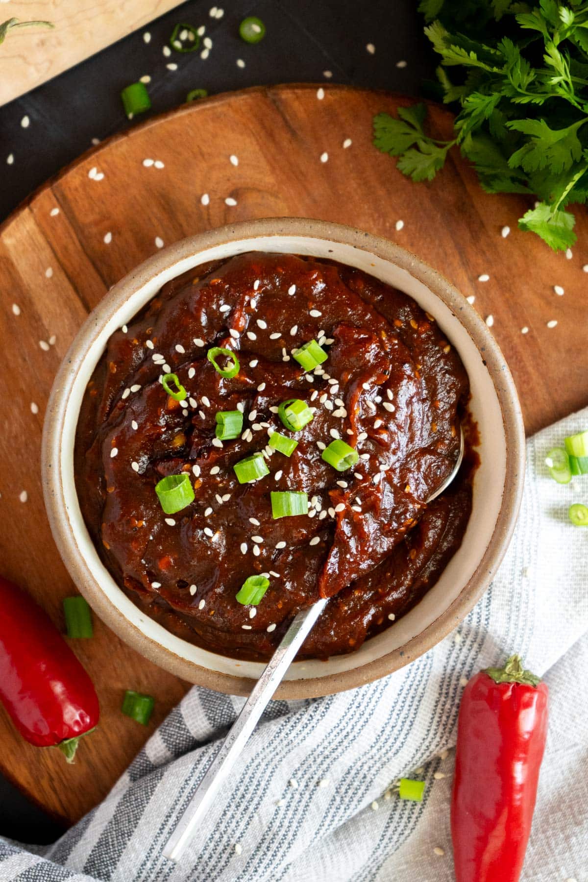 Korean BBQ sauce in a bowl with green onions and sesame seeds.