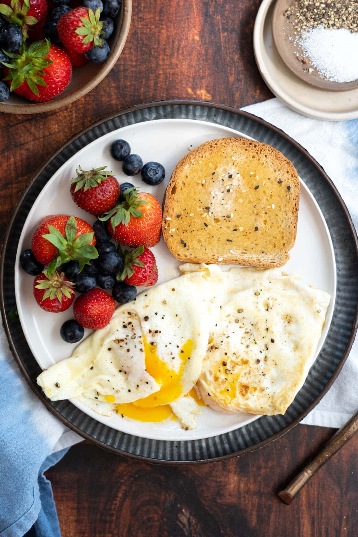 A breakfast plate with over easy eggs, toast and fresh berries.