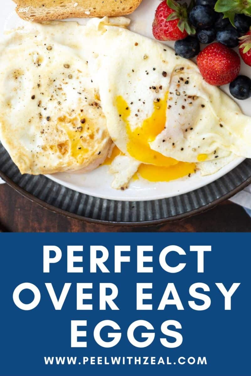 Over easy fried eggs on a plate with fruit.