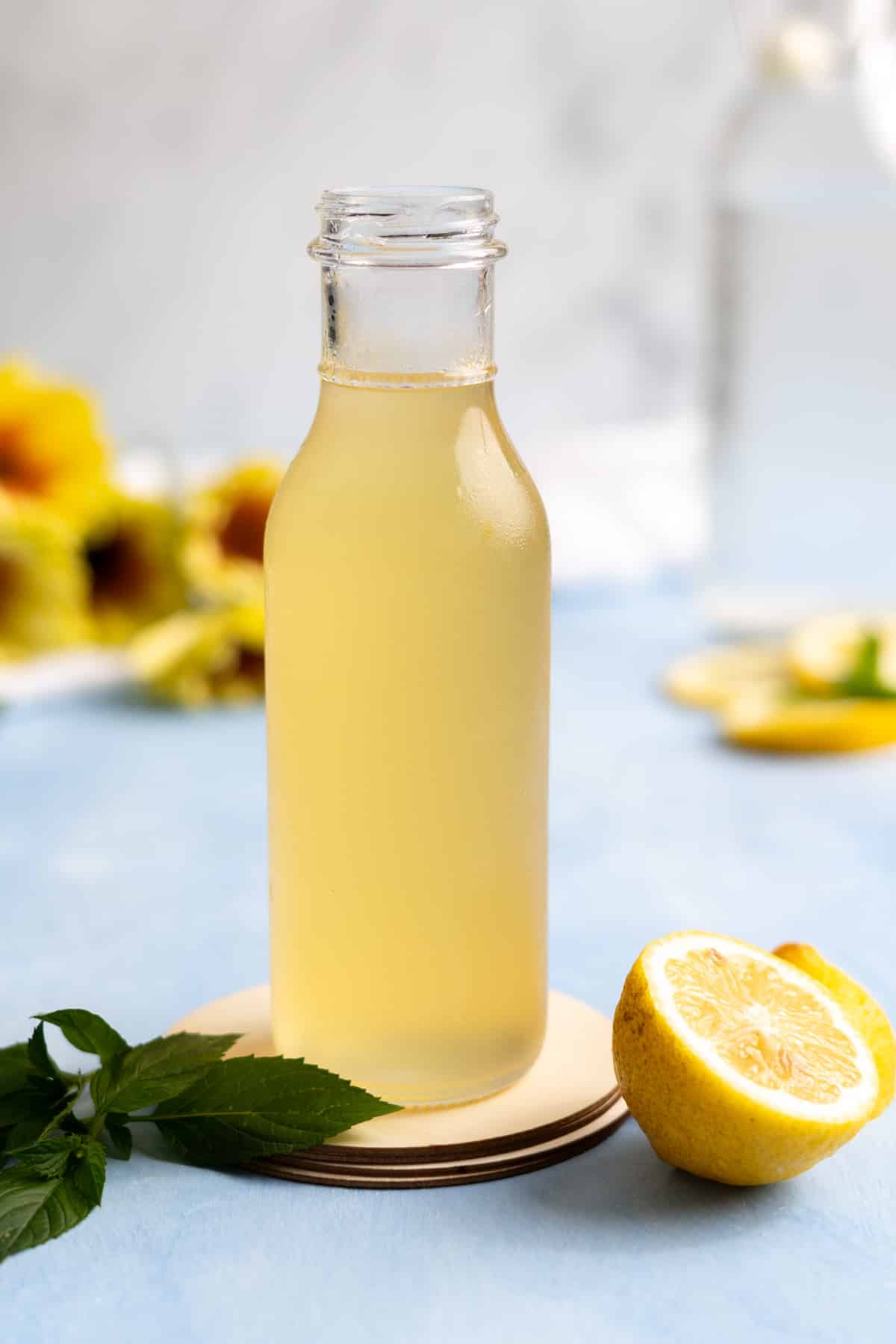 Chilled bottle of lemon syrup with mint leaves and fresh lemons.