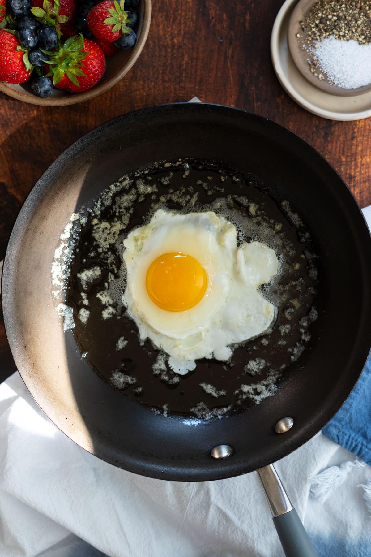 A cracked egg in a non-stick pan.