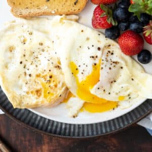 A breakfast plate with over easy eggs, toast and fresh berries.
