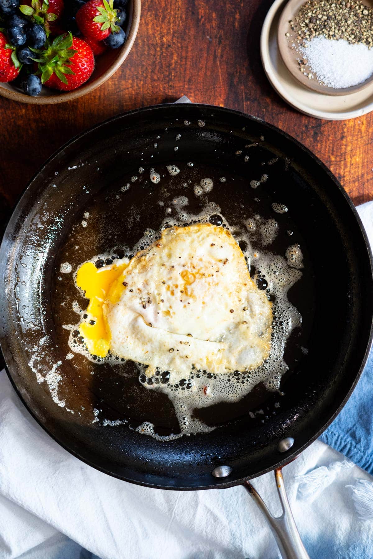 Fried egg with a broken yolk in a frying pan.