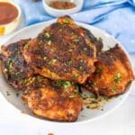 Grilled bbq chicken thighs on a white plate.
