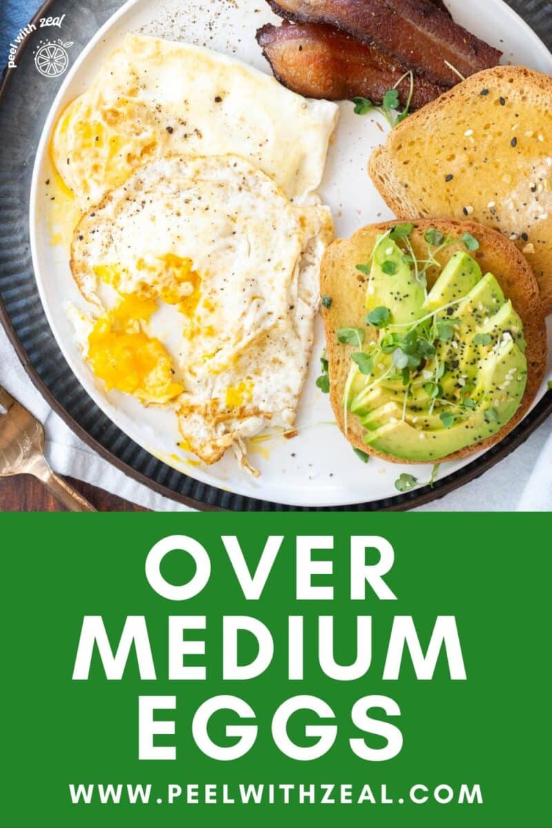 Over medium eggs on a plate with bacon, fruit and avocado toast.