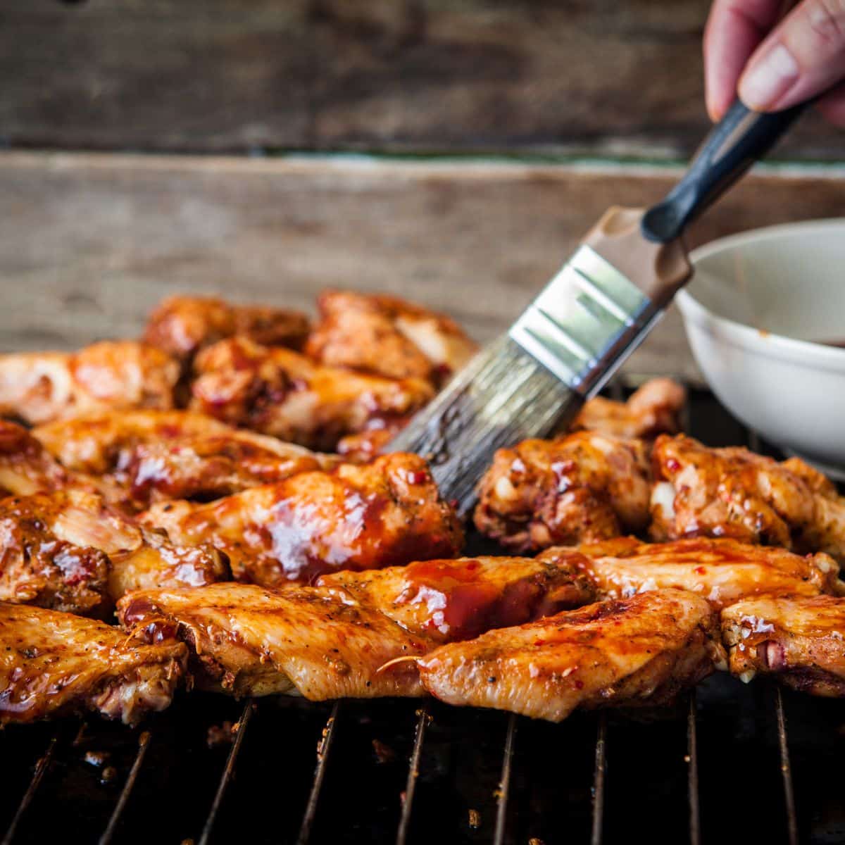 Brushing on a thinned BBQ sauce onto grilled chicken.