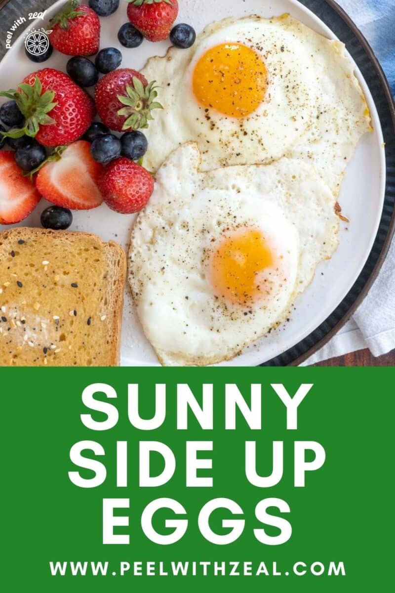 Sunny side up eggs on a plate with toast and fruit.
