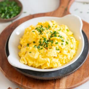 Cheesy scrambled eggs and toast on a plate.