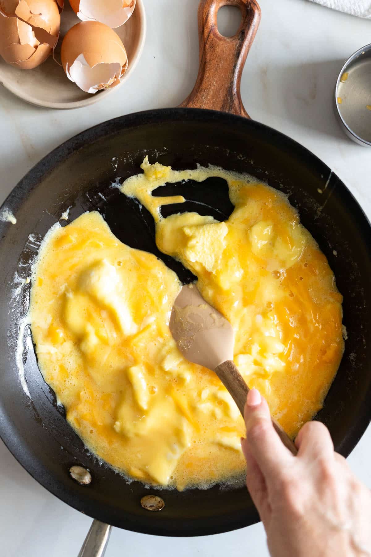 Creating soft egg curds with a spatula.
