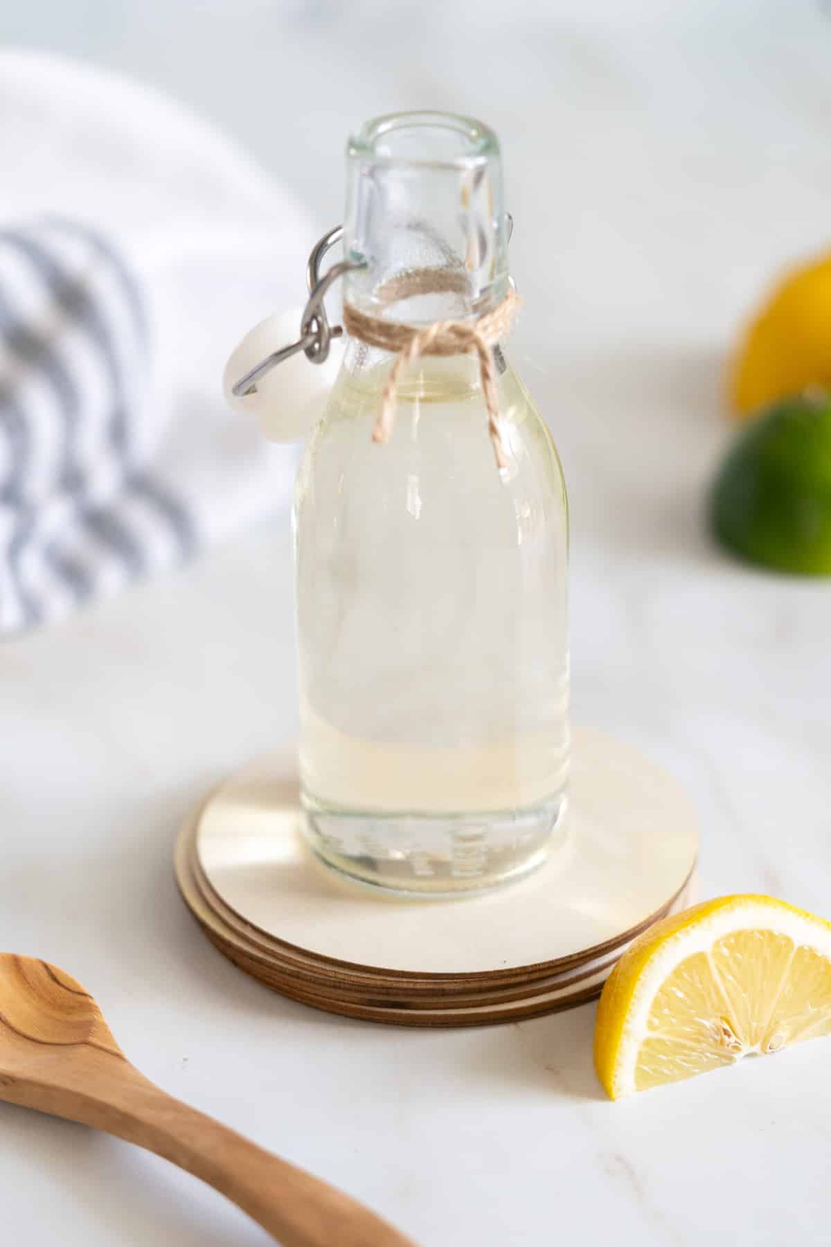 Simple syrup in a bottle with a slice of lemon and wooden spoon.