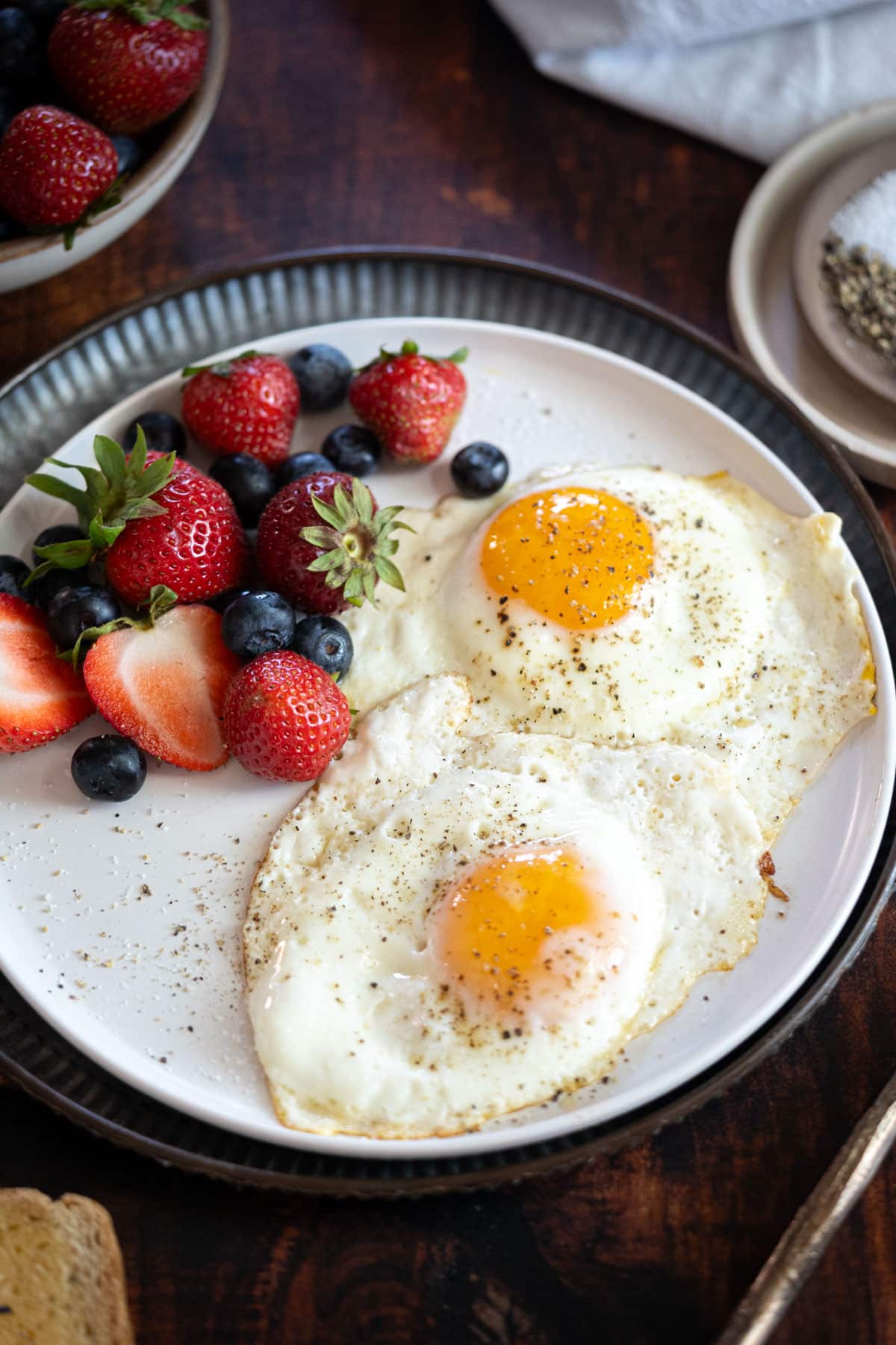 Sunny side up eggs with a plate of fruit.