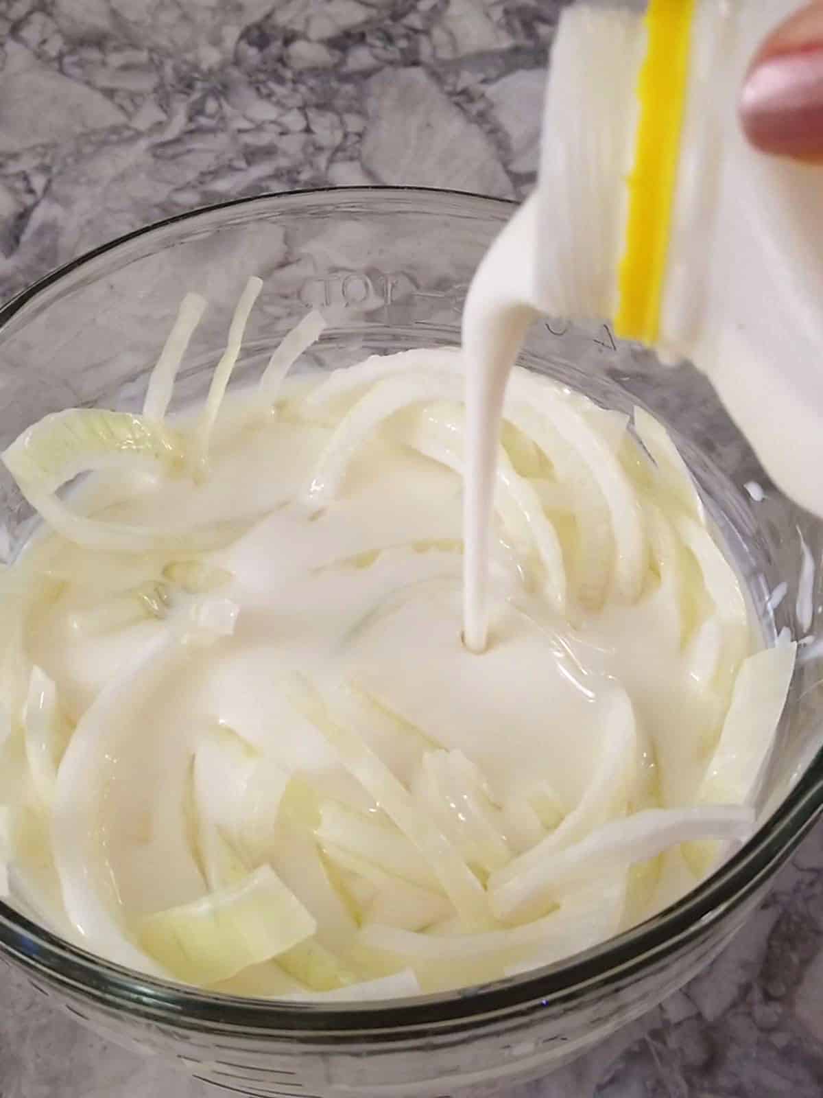 Pouring buttermilk over the sliced onions.