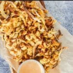 Onion straws on a plate with fry sauce.