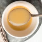 A spoon lifting gluten-free roux out of the bowl.