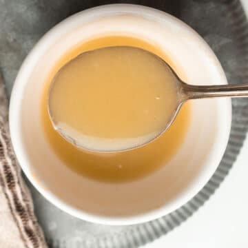 A spoon lifting gluten-free roux out of the bowl.