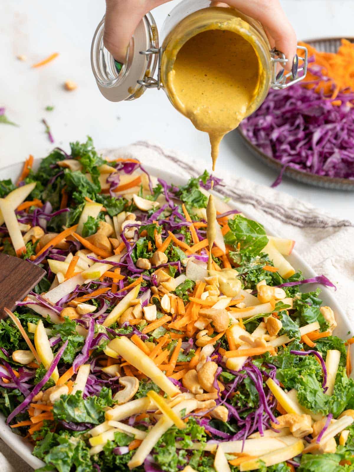 Pouring dressing on a kale slaw.