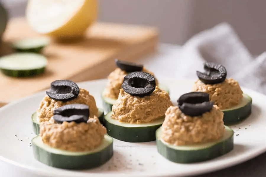 Sardine spread on top of cucumber slices topped with olive slices.
