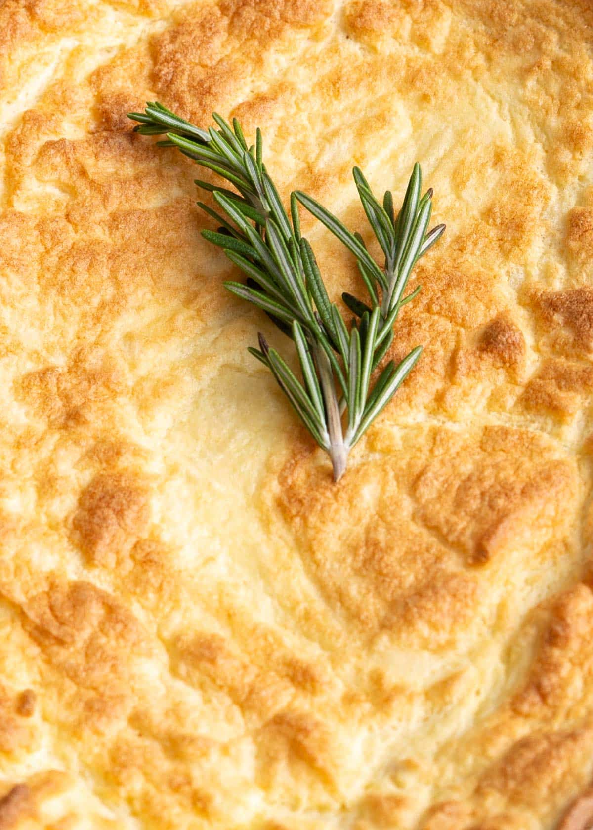 Top of potato souffle with fresh rosemary.