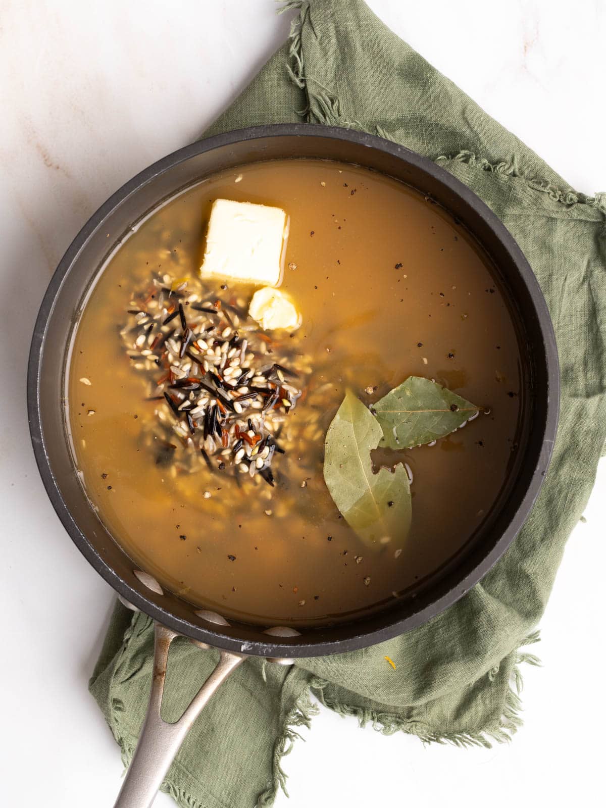 Rice, broth, and butter in a pot.