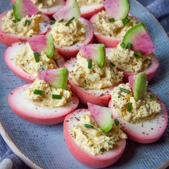Beet pickled deviled eggs garnish with watermelon radish.