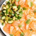 Salmon Crudo with a side of spicy cucumber slices.