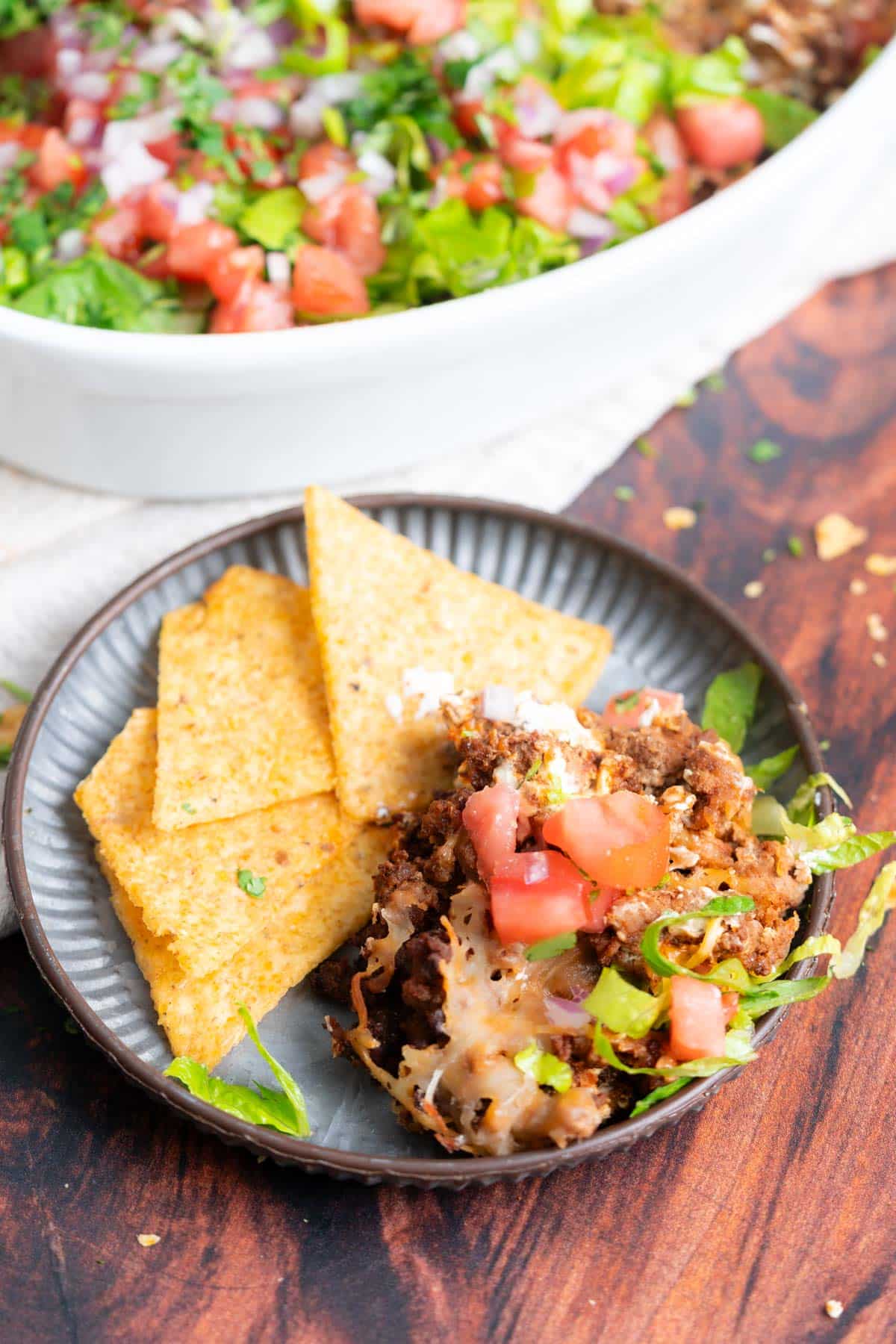 plate of tortilla chips with layered beef taco dip. 