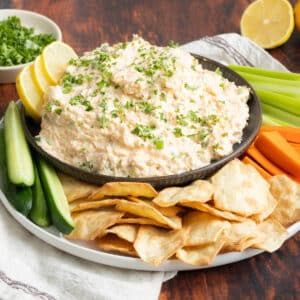 Cajun crab dip in a bowl with sides of vegetables and crackers.